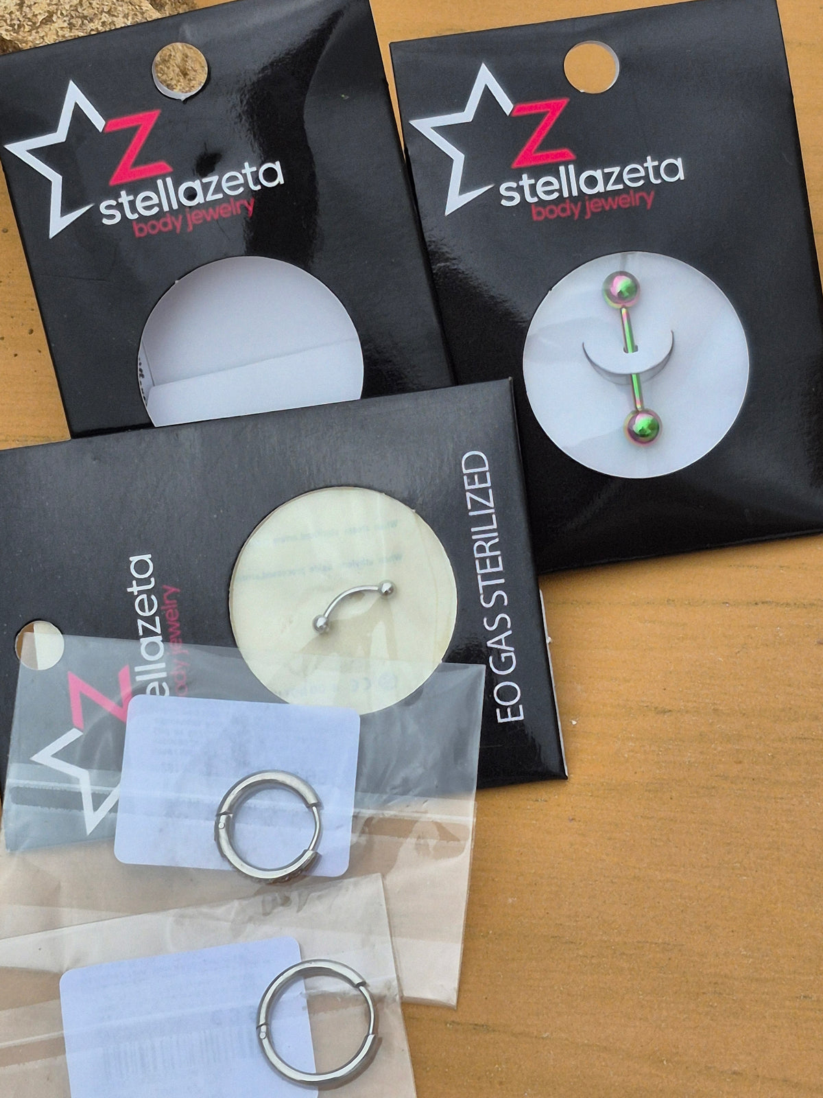 Trois piercings Stellazeta : anneau, barre courbée et modèle à embouts colorés